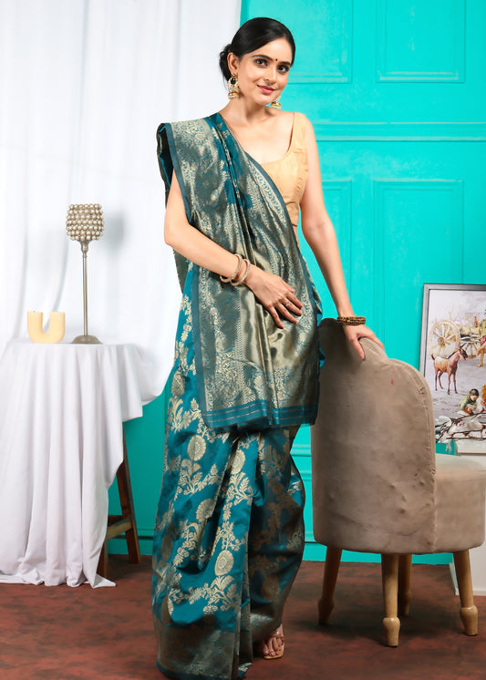 Full-length view of a woman adorned in an Emerald Green Banarasi silk saree, styled with minimalistic gold jewelry, standing against a vibrant backdrop.