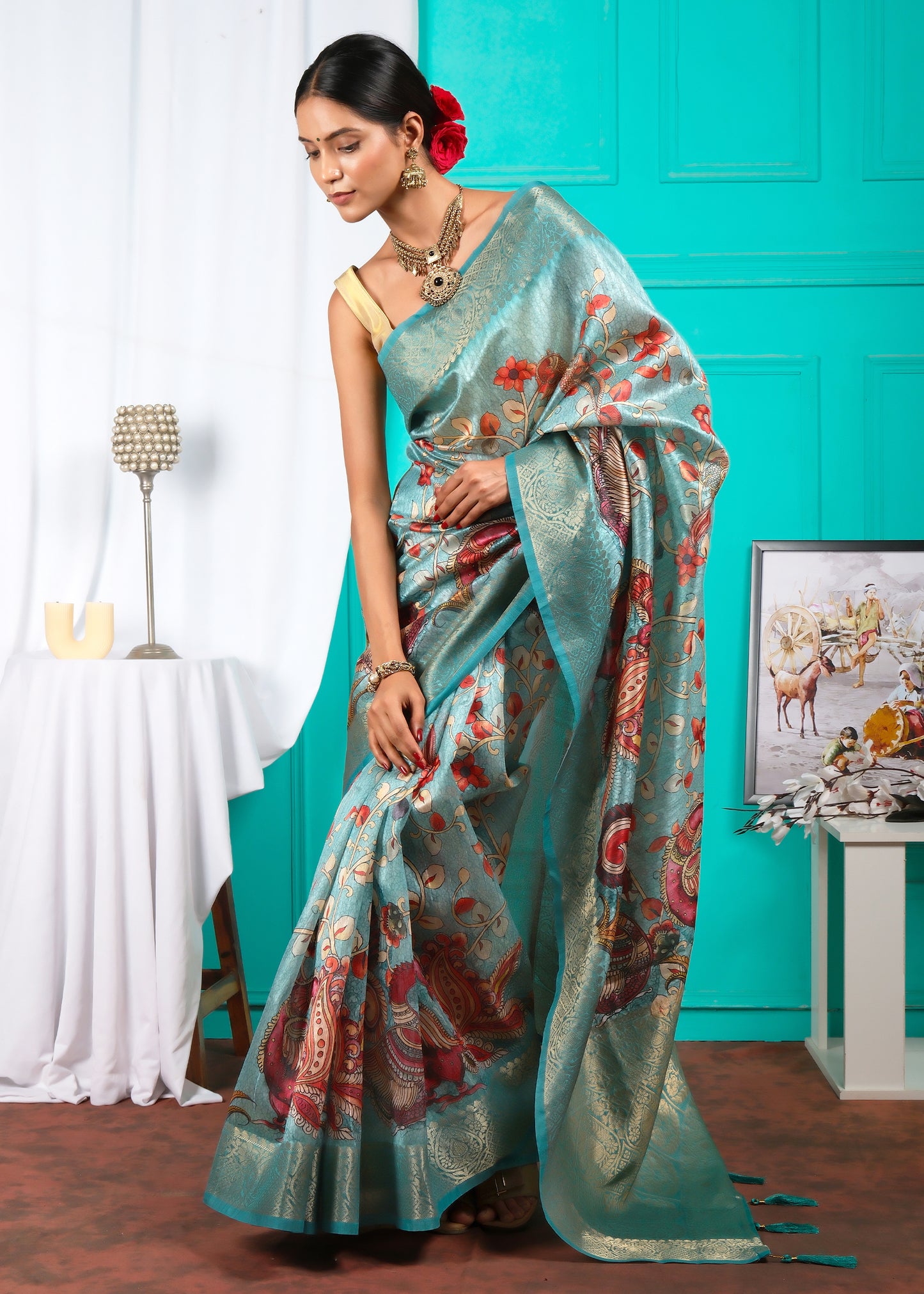 Full view of a teal silk saree with peacock and floral designs, styled with traditional jewelry and accessories, perfect for festive and wedding occasions.