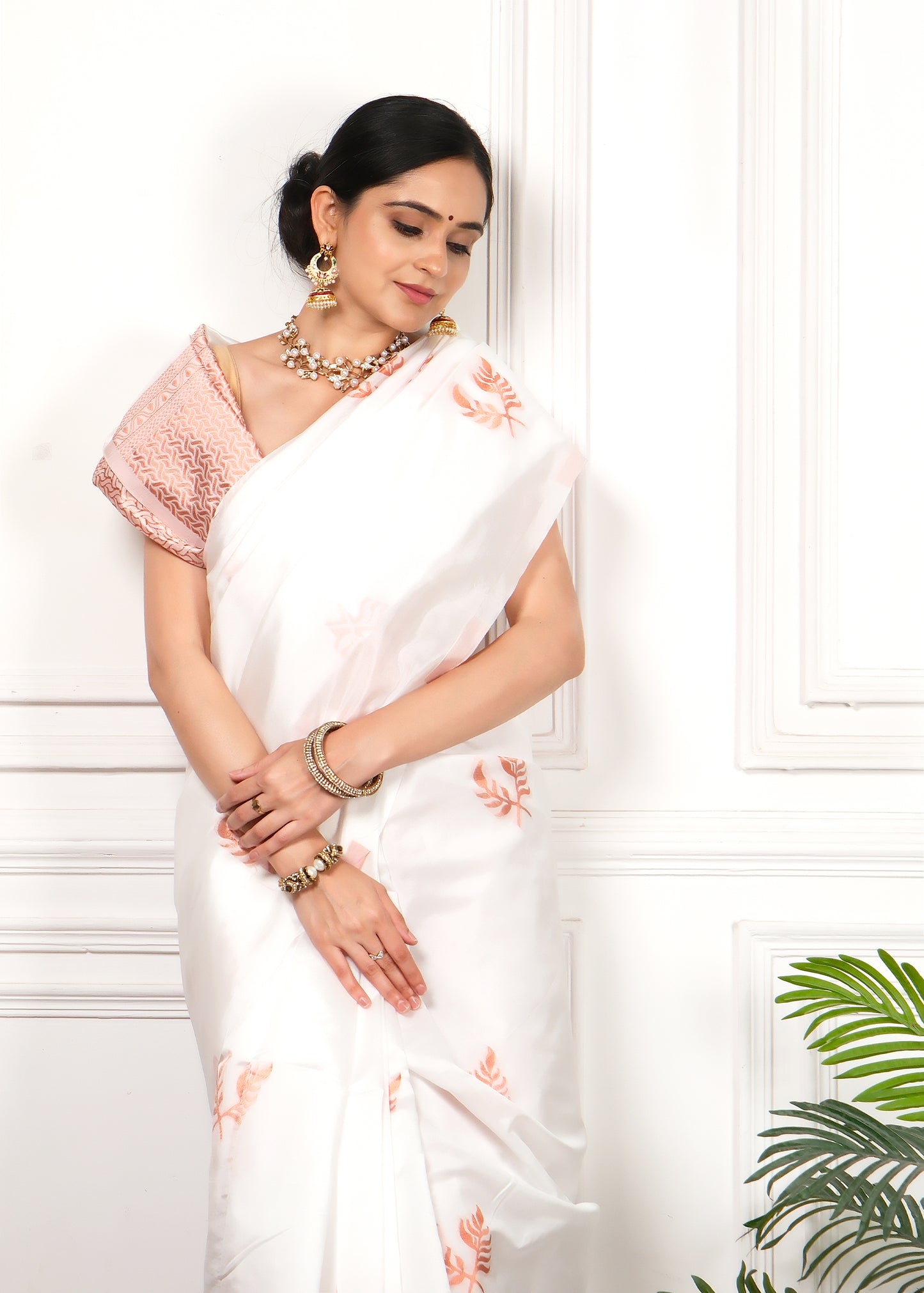 Graceful and elegant model dressed in a white and orange handwoven silk saree, complemented with traditional jewelry and soft lighting