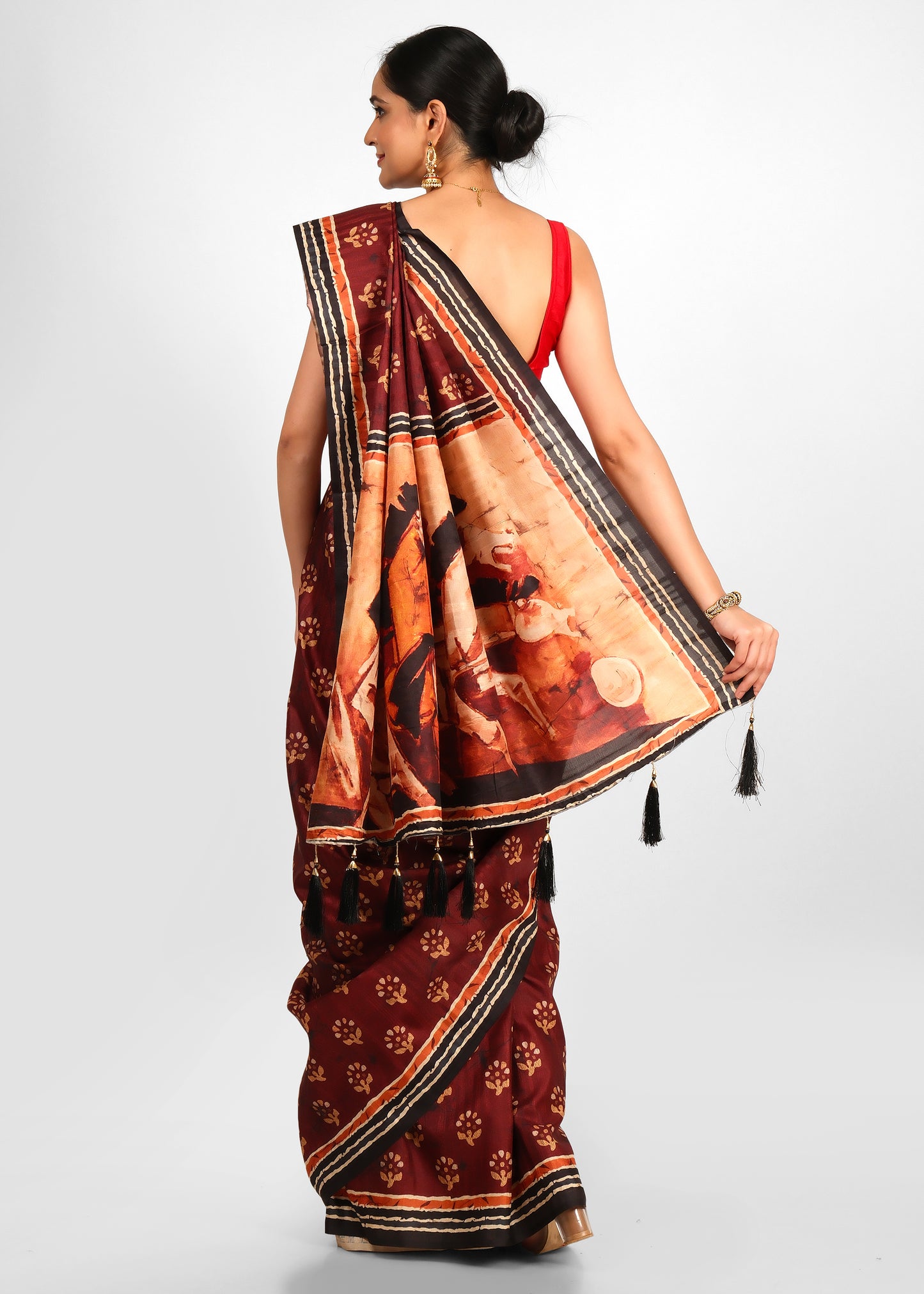 Rear view of a woman flaunting the Kalamkari pallu with detailed artwork on a maroon art silk saree.