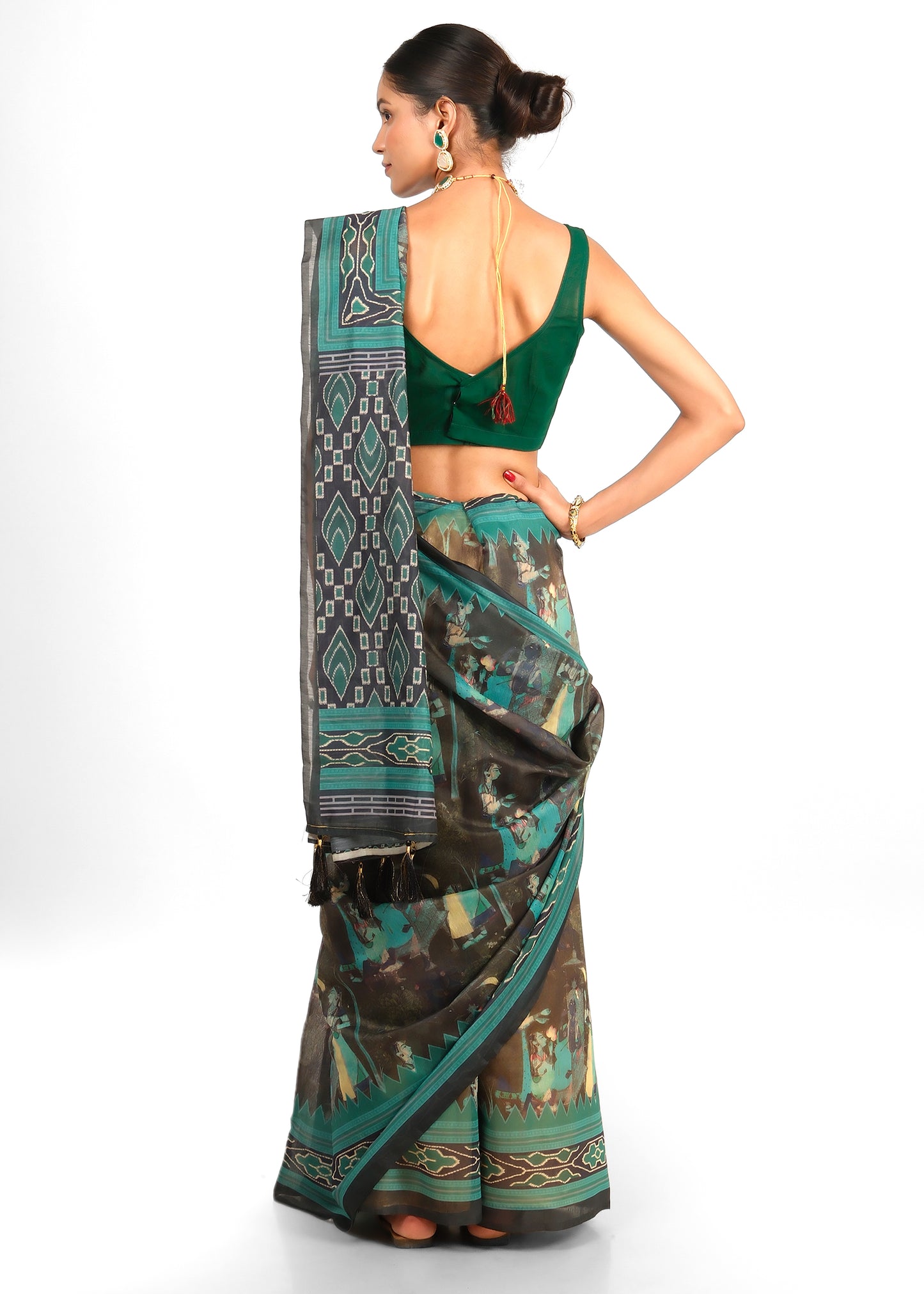 Back view of a model showcasing the back design of the blouse and the intricate border of her green saree with tassels