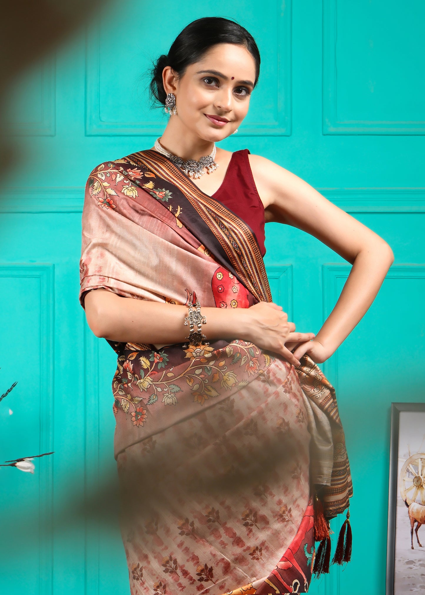 Model wearing a beige saree with maroon blouse, showcasing the intricate designs and detailing