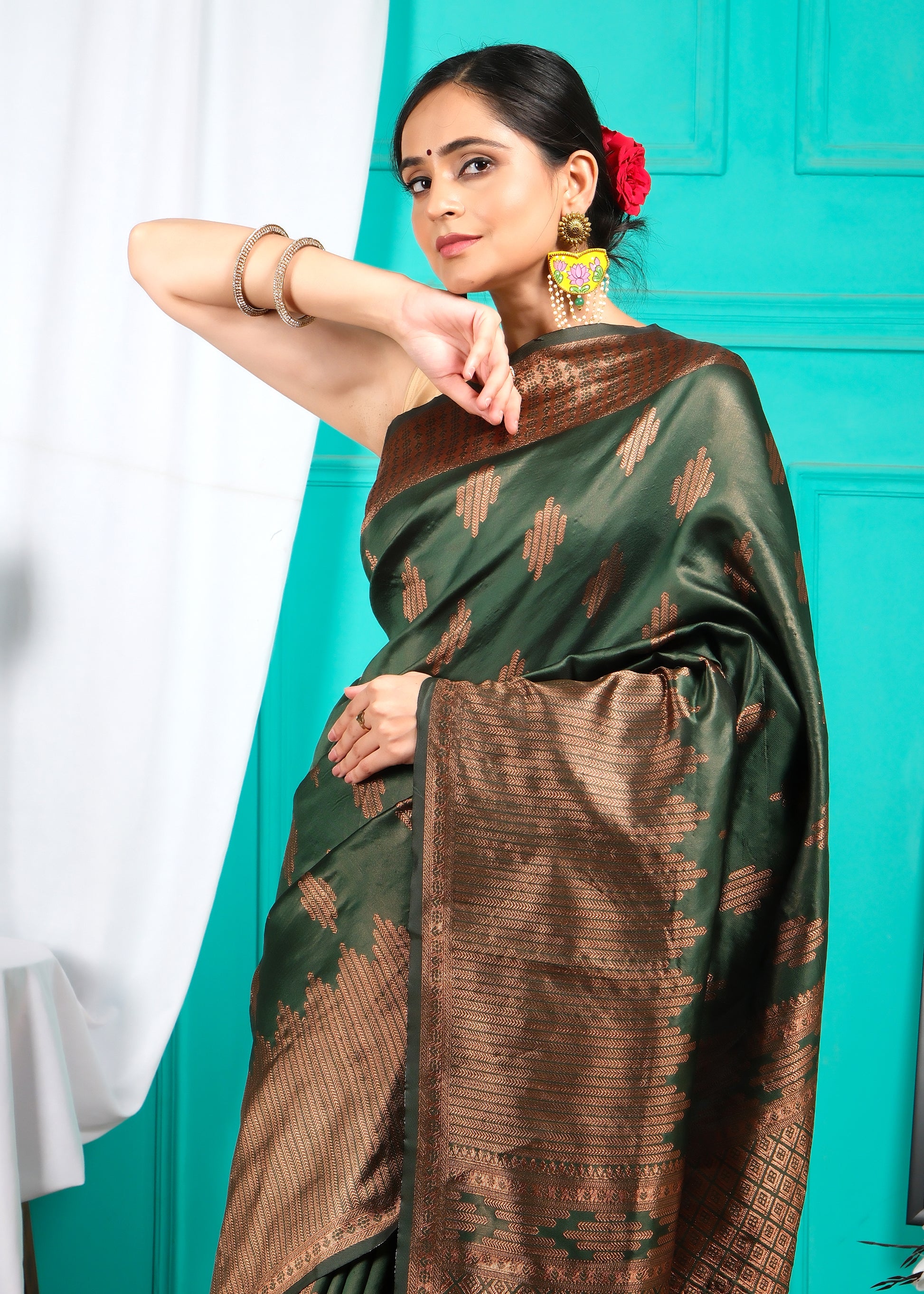 Close-up of a woman in a green and brown silk saree with intricate gold designs, emphasizing traditional Indian attire