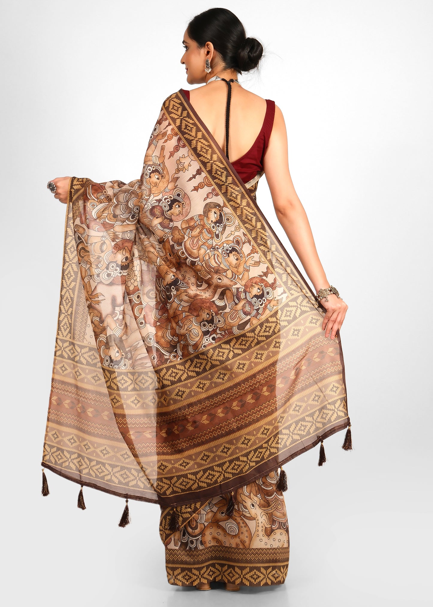 Back view of a woman wearing a hand-printed saree with mythological motifs, detailed with tassels on the pallu, exuding traditional charm