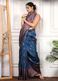 Side pose of model in royal blue silk saree, paired with golden accessories and copper zari design