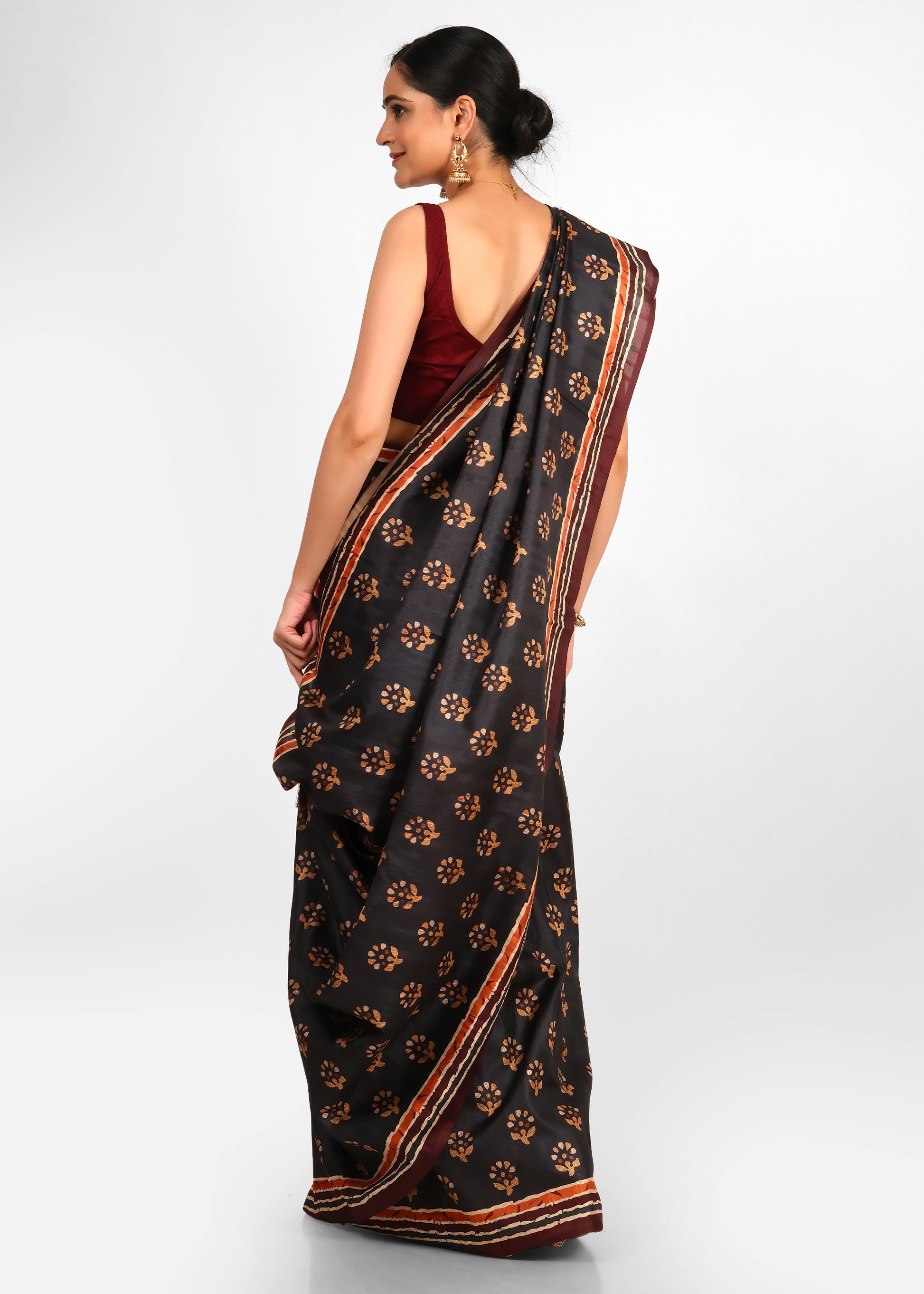 Rear view of a woman wearing a black floral printed saree with maroon blouse, showcasing the beautiful draping of the saree