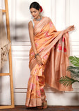 Peach-colored Banarasi silk saree with silver zari work and pink floral embroidery, styled beautifully by a model