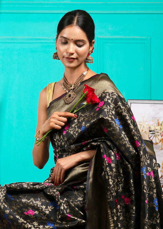 Elegant model holding a red rose, draped in a black Banarasi silk saree with gold zari and vibrant floral motifs