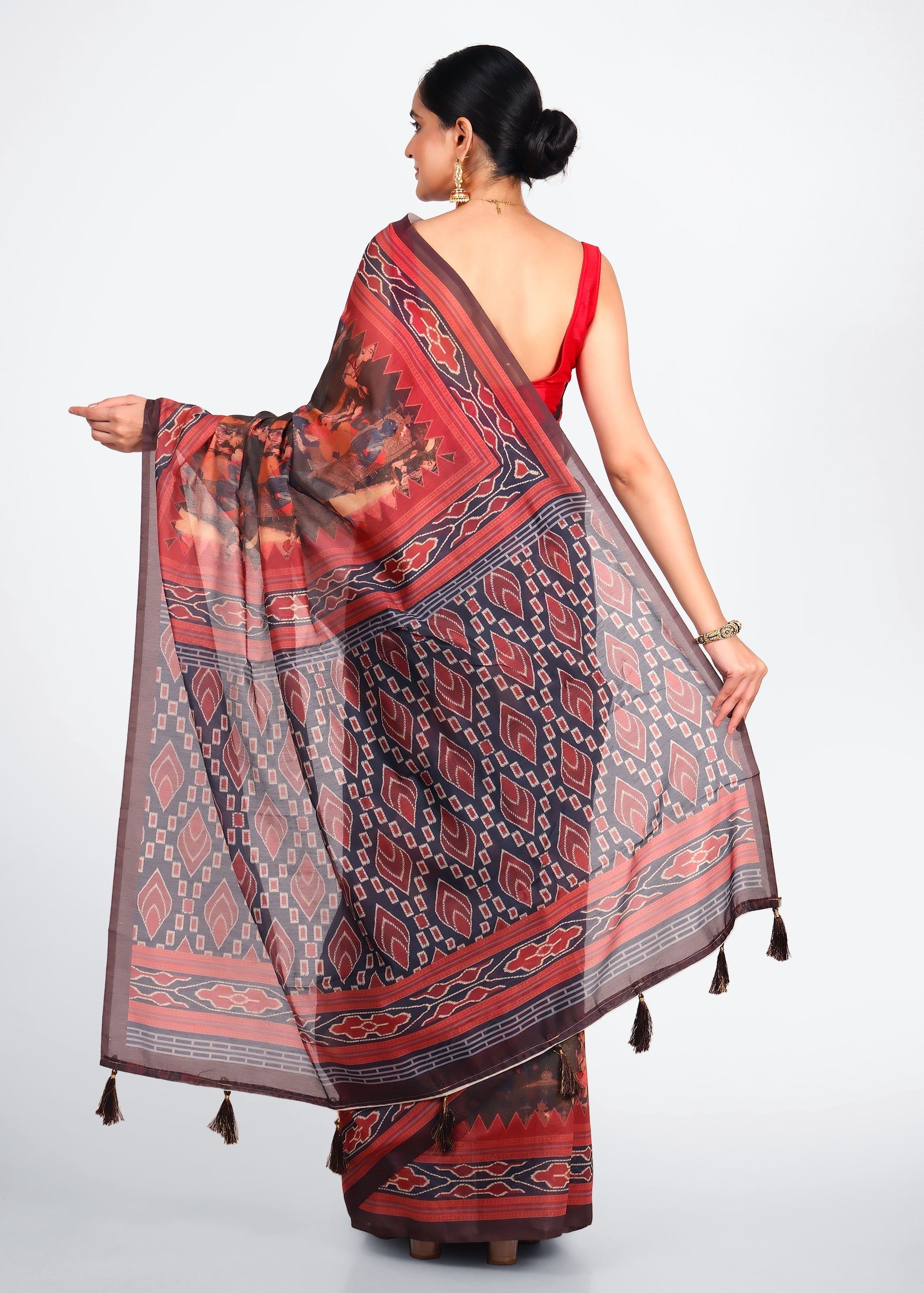 Rear view of a woman showcasing the beautiful pallu of a handwoven Ikat saree with tassel details.