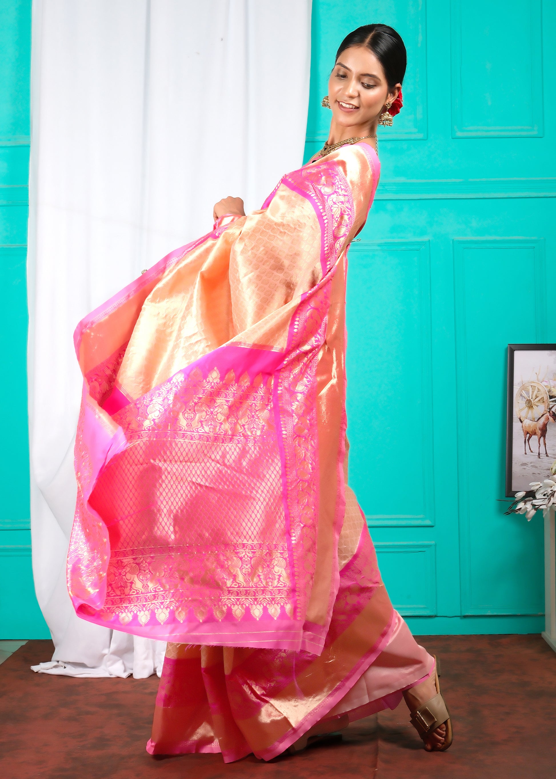 Full view of a model twirling in a luxurious peach and pink silk saree, capturing the movement and sheen of the fabric