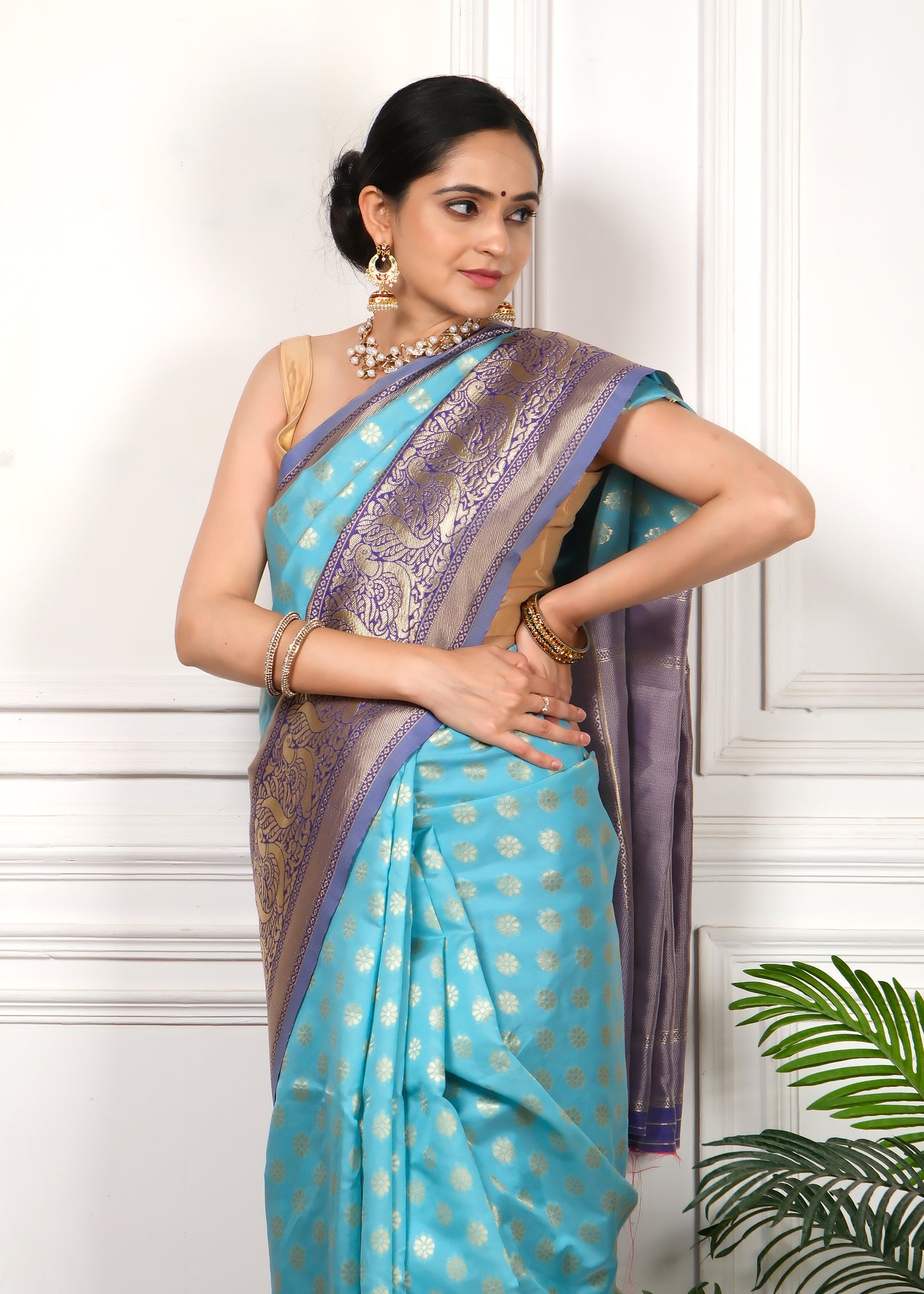 Close-up shot of a turquoise blue silk saree with gold and purple detailing, capturing the luxurious texture and design for a sophisticated ethnic ensemble